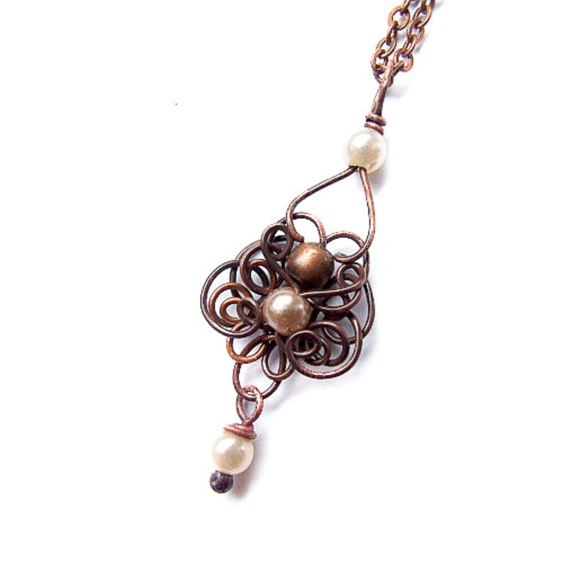 May include: A copper wire necklace with a delicate, intricate design featuring a cluster of small, off-white pearls. The necklace has a simple chain and a single pearl dangling from the bottom.