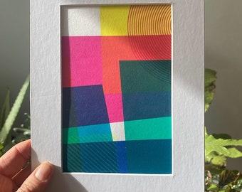 Könnte beinhalten: Ein gerahmter abstrakter Druck mit geometrischen Formen in leuchtenden Farben, darunter Gelb, Rot, Pink, Blau und Grün.