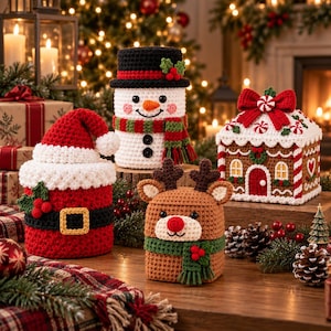 May include: A collection of four crocheted holiday decorations including a red Santa Claus container, a white snowman with a black hat, a brown reindeer with antlers and a red nose, and a square gingerbread house box with a red bow on top.
