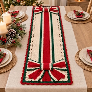 Pode incluir: Um caminho de mesa retangular em crochê com uma faixa central vermelha ladeada por bordas verdes e creme. O caminho é decorado com dois grandes laços de crochê tridimensionais em vermelho e verde em cada extremidade e uma borda festonada.