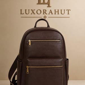 May include: A dark brown leather backpack featuring gold-tone metal zippers, a top handle, adjustable shoulder straps, and two front zippered pockets. The brand name LUXORAHUT and a stylized LH logo are visible in the background above the backpack.