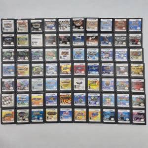 May include: A collection of eighty Nintendo DS video game cartridges arranged in an eight-by-ten grid. Each rectangular plastic cartridge features a label with colorful artwork, the game title, and the Nintendo DS logo at the top.