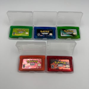 May include: Five Nintendo Game Boy Advance video game cartridges in clear plastic cases. The collection includes Pok&eacute;mon LeafGreen, Sapphire, Emerald, FireRed, and Ruby versions, each featuring its respective colored casing and game label.