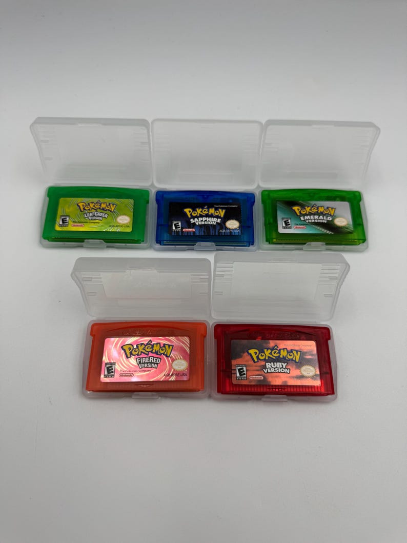 May include: Five Nintendo Game Boy Advance video game cartridges in clear plastic cases. The collection includes Pok&eacute;mon LeafGreen, Sapphire, Emerald, FireRed, and Ruby versions, each featuring its respective colored casing and game label.