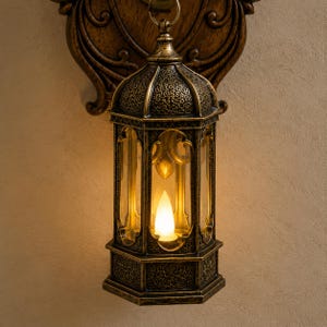 Op de afbeelding: Een wandlantaarn met een antieke bronsafwerking en ingewikkelde reli&euml;fdetails. Het zeshoekige frame bevat heldere glazen panelen en een centrale vlamvormige gloeilamp. Het is bevestigd aan een decoratieve houten wandsteun.