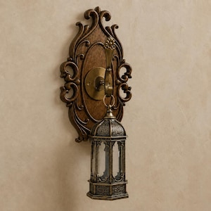 Op de afbeelding: Een wandlamp met een donkerbruine, sierlijke houten achterplaat met krulwerk. Een messingkleurige metalen haak steekt uit het midden en draagt een kleine, zeshoekige lantaarn met ingewikkelde metalen filigraanpatronen.
