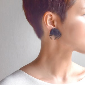 May include: A pair of black geometric earrings with a fan-like design. The earrings are made of metal and have a matte finish.