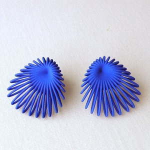 May include: A pair of blue earrings with a unique, geometric design. The earrings are made of metal and have a starburst shape.
