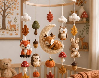 May include: A woodland-themed nursery mobile featuring crocheted figures of a sleeping deer on a crescent moon, a fox, an owl, a rabbit, a hedgehog, mushrooms, pumpkins, acorns, leaves, and clouds suspended from a circular wooden frame.