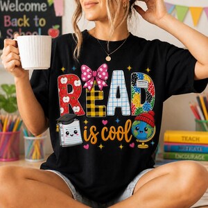 Peut inclure: Un t-shirt noir avec le texte READ is cool. Les lettres sont décorées de motifs de pommes, de carreaux jaunes, de lignes quadrillées et de confettis colorés. Un carnet souriant avec une toque et un globe avec un bonnet rouge sont inclus.