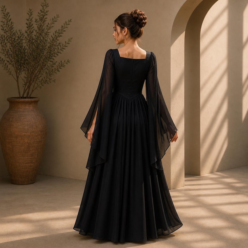 May include: A floor-length black dress featuring a square neckline and long, flowing bell sleeves. The garment has a fitted bodice that transitions into a full, pleated skirt made of a sheer, lightweight fabric that drapes to the floor.