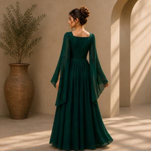 May include: A floor-length dark emerald green dress featuring long, flowing bell sleeves and a square neckline. The garment has a fitted bodice that transitions into a full, pleated skirt, showcasing a solid color and a lightweight, sheer fabric.