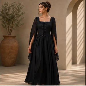 May include: A floor-length black dress featuring a square neckline, a lace-up corset-style bodice with vertical eyelets, and long, flowing sheer sleeves. The skirt is full and gathered at the waist, creating a voluminous silhouette in solid black.