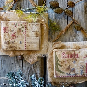 May include: Two vintage-style Christmas ornaments with embroidered designs. One ornament features a letter to Santa with the text "Dear Santa define good". The other ornament features a Santa Claus figure with the text "Santa".