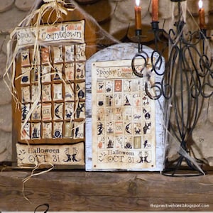 Könnte beinhalten: Zwei gerahmte Kreuzstich-Bilder mit einem gruseligen Halloween-Countdown-Motiv. Die Rahmen sind aus Holz und haben eine abgenutzte Oberfläche. Die Kreuzstich-Bilder sind beide mit "Spooky Countdown" betitelt und zeigen eine Vielzahl von Halloween-Motiven, darunter Kürbisse, Fledermäuse, Geister und Hexen. Der Text "Halloween OCT 31" ist ebenfalls auf beiden Bildern enthalten.
