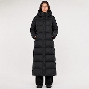 Peut inclure: Un long manteau doudoune noir matelassé doté d'un col montant, d'une capuche et d'une patte de boutonnage avant avec des boutons-pression visibles. Le manteau descend jusqu'au bas du mollet et possède des manches longues à bords-côtes.