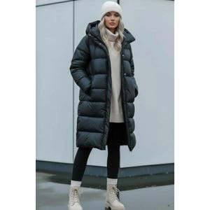 May include: A long black puffer coat with a hood, worn over a beige turtleneck sweater, black leggings, and beige lace-up boots. The coat features a front zipper closure and horizontal quilted panels, providing a layered look with neutral tones.
