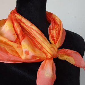 Pañuelo cuadrado de seda coral pintado a mano. Rosa salmón, amarillo y rojo coral. 66 x 66 cm. Diseño floral en colores cálidos. Pañuelo pequeño.