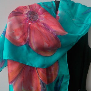 May include: A turquoise silk scarf with a hand-painted design of red and orange flowers.