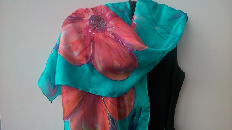 May include: A turquoise silk scarf with a hand-painted design of red and orange flowers.