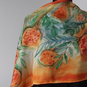 May include: A silk scarf with a watercolor design of orange fruit and green leaves on a yellow and orange background.