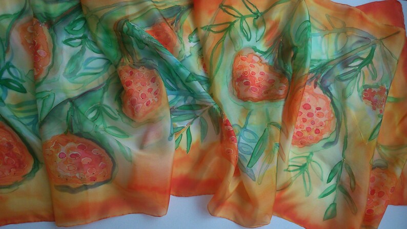 May include: A silk scarf with a watercolor design of orange and red fruits with green leaves on a yellow and orange background.