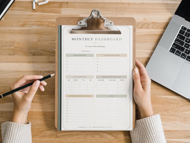 May include: A monthly dashboard planner sheet on a brown clipboard with a silver metal clip. The white paper features sections for major priorities, to-do lists, meetings, inventory, and notes, with the text Monthly Dashboard and September.