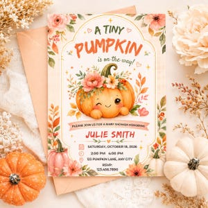 May include: A rectangular baby shower invitation card featuring a central illustration of a smiling, winking orange pumpkin adorned with pink and white flowers. The text reads A TINY PUMPKIN is on the way! PLEASE JOIN US FOR A BABY SHOWER HONORING JULIE SMITH, SATURDAY, OCTOBER 18, 2026, 2:00 PM 4:00 PM, 123 PUMPKIN LANE, ANY CITY, RSVP: 123.456.7890.