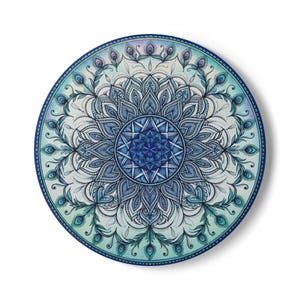 Puede incluir: Una pieza de arte mural circular con un diseño de mandala detallado en tonos azul, turquesa y blanco. La obra muestra patrones simétricos complejos, incluyendo motivos de plumas de pavo real estilizadas que irradian desde un centro azul oscuro.