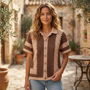 Puede incluir: Una camisa de ganchillo de manga corta con botones, que presenta un panel central de punto gofrado marrón y paneles laterales de color beige con patrón de granny square. La prenda incluye un cuello clásico, tapeta y dobladillo.