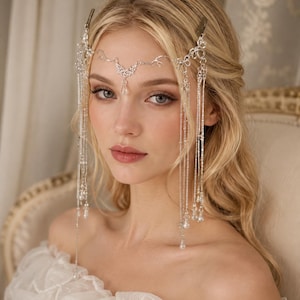 May include: A silver-toned headpiece featuring intricate filigree metalwork across the forehead, accented with delicate hanging chains and clear teardrop-shaped crystals that drape down the sides of the face, secured with metal hair clips.