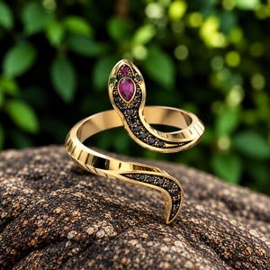 May include: A gold-toned wrap ring shaped like a snake, featuring a marquise-cut red stone on the head, two small green accent stones, and a series of small black stones embedded along the head and tail sections of the snake's body.