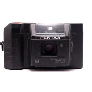 Peut inclure: Un appareil photo argentique compact noir de marque Pentax avec un objectif 35mm f/3.5, autofocus et codage DX. La face avant affiche le nom de la marque Pentax, les spécifications de l'objectif et un petit bouton rouge sur le dessus.