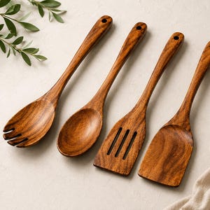 May include: A set of four brown wooden kitchen utensils featuring a salad fork with three tines, a solid oval spoon, a slotted spatula with three vertical openings, and a solid flat spatula, each with a circular hole at the end of the handle.