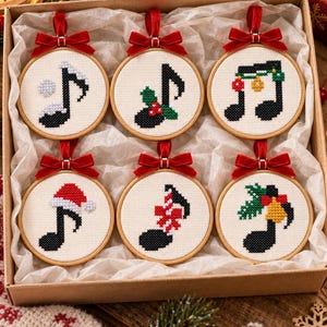 May include: A set of six circular wooden embroidery hoops containing cross-stitch music notes decorated with holiday elements like holly, a Santa hat, and bells. Each hoop features a red velvet ribbon bow at the top for hanging purposes.
