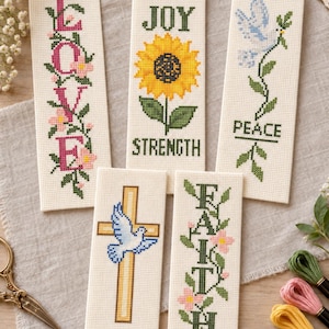 May include: Five rectangular cross-stitch bookmarks on cream Aida cloth. Designs include the word LOVE with pink flowers, a sunflower with the word STRENGTH, a dove with the word PEACE, a gold cross with a blue dove, and the word FAITH with pink flowers.