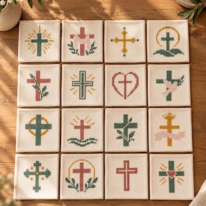May include: A set of sixteen square fabric coasters arranged in a four-by-four grid, each featuring a unique cross-stitch design. The motifs include various styles of crosses, hearts, and floral elements in shades of green, pink, and yellow.