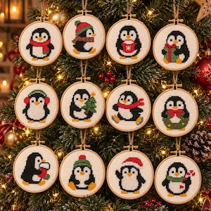 May include: Twelve circular wooden embroidery hoops containing cross-stitch designs of penguins. Each penguin features different winter accessories like scarves, hats, earmuffs, or holiday items such as a Christmas tree, a gift, a wreath, and a candy cane.
