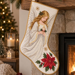 Puede incluir: Un calcetín navideño blanco con un diseño de punto de cruz de un ángel con cabello rubio largo, alas grandes y una vela encendida. El calcetín está decorado con un borde dorado y una flor de pascua roja grande con hojas verdes en la base.