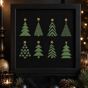 May include: A framed cross-stitch artwork featuring eight distinct green Christmas tree designs arranged in two rows on a black fabric background. Each tree is topped with a small yellow star, showcasing varied geometric patterns and shapes.