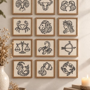 Pode incluir: Uma coleção de doze obras de arte em ponto cruz com molduras quadradas dispostas em grade, cada uma apresentando um símbolo do zodíaco bordado em preto sobre tecido creme, incluindo Áries, Touro, Gêmeos, Câncer, Leão, Virgem, Libra, Escorpião, Sagitário, Capricórnio, Aquário e Peixes.