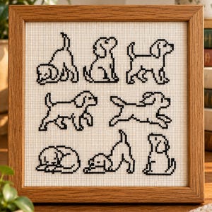 May include: A square wooden frame containing a cross-stitch embroidery on white fabric. The design features seven black-stitched dog silhouettes in various poses, including sitting, running, sleeping, and stretching, arranged in three rows.