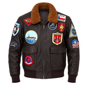 May include: A dark brown leather bomber jacket featuring a brown faux fur collar, a front zipper closure, and two front flap pockets. The jacket is decorated with numerous colorful embroidered military-style patches, including a Texas flag patch.