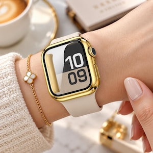 Pode incluir: Um smartwatch com caixa retangular em tom dourado polido e pulseira de silicone bege lisa. O mostrador digital exibe a hora 10:09 em fonte preta em negrito. Uma delicada pulseira de corrente dourada com um pingente de trevo de quatro folhas.