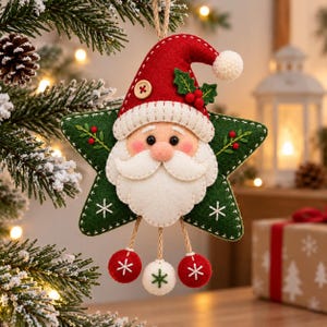 Könnte beinhalten: Ein Weihnachtsanhänger aus Filz in Form eines grünen Sterns mit einem Weihnachtsmann-Gesicht und roter Mütze. Der Stern ist mit weißen gestickten Schneeflocken und grünen Stechpalmenblättern verziert. Drei Filzkugeln hängen an der Unterseite.