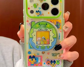 Könnte beinhalten: Eine transparente Handyhülle mit hellgrünem Rand, verziert mit bunten Cartoon-Aufklebern von Charakteren an Computern und einem runden, ausklappbaren Tamagotchi-Griff in der Mitte. Das Design enthält kleine Sterne, Noten und Text.