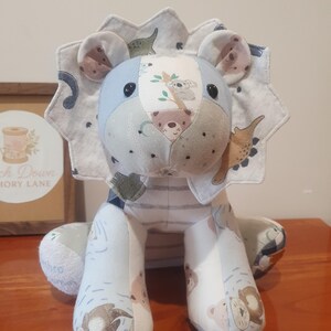 May include: A stuffed lion toy constructed from various patterned fabric patches in shades of blue, white, and grey. The lion features a jagged mane, black button eyes, and a printed design showing koalas, bears, and other small animal illustrations.