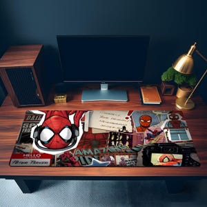 May include: A rectangular desk mat featuring a collage of Spider-Man comic book imagery, including a large central mask graphic, a Lego-style figure, a camera displaying a photo of the character, and text reading "Your Friendly Neighborhood Spider-Man."