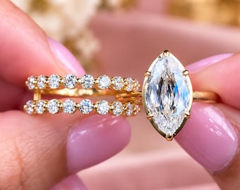 Op de afbeelding: Een gouden ringenset bestaande uit een ring met een marquise-geslepen middensteen in een zetting en een bijpassende ring met twee rijen kleine, ronde stenen. De sieraden zijn vervaardigd van gepolijst geelgoud met witte stenen.