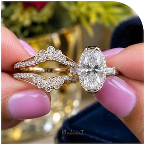 Puede incluir: Un conjunto de anillos de oro compuesto por una piedra central de corte ovalado rodeada por un halo de pequeños diamantes redondos y dos piedras laterales de corte baguette, junto a un anillo protector curvo con diseño de abanico y diamantes.